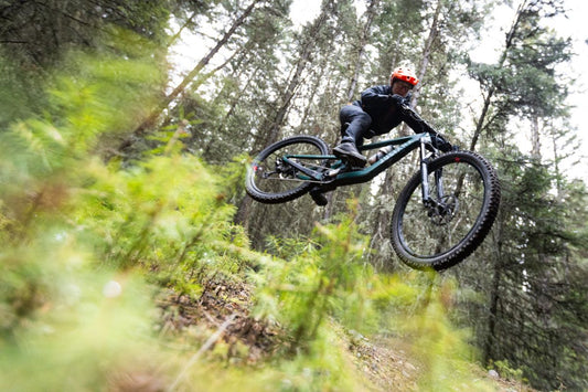 Mountain bike riding downhill in the air like the bike is flying.