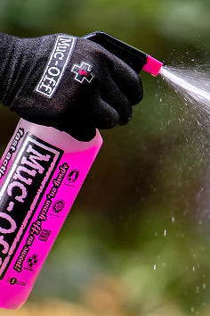 Person cleaning bicycle chain with Muc-Off cleaning spray