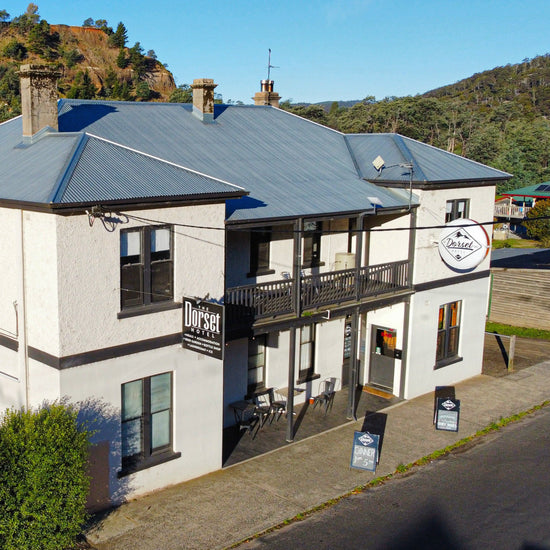 Two-story building with a clock on a sunny day, surrounded by trees and mountains.